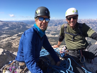 Two men sitting on a cliff face after rock climbing