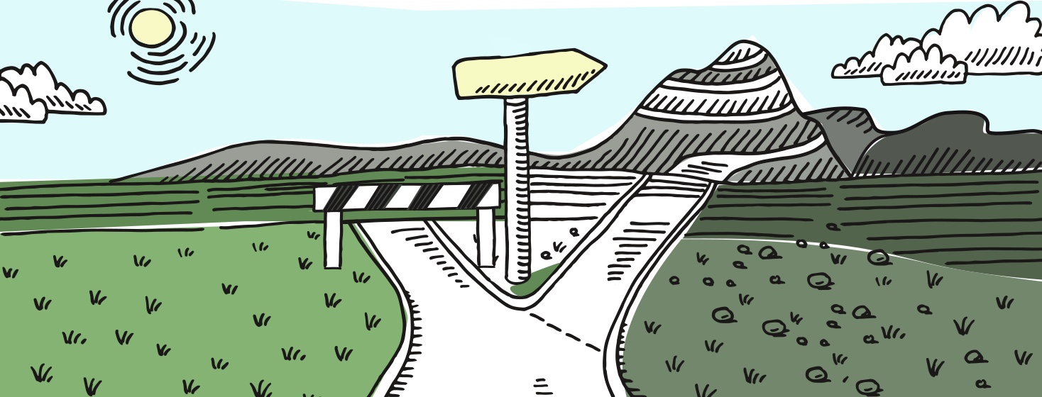 A road splits into two paths, with one path blocked off and the other going into the mountains.