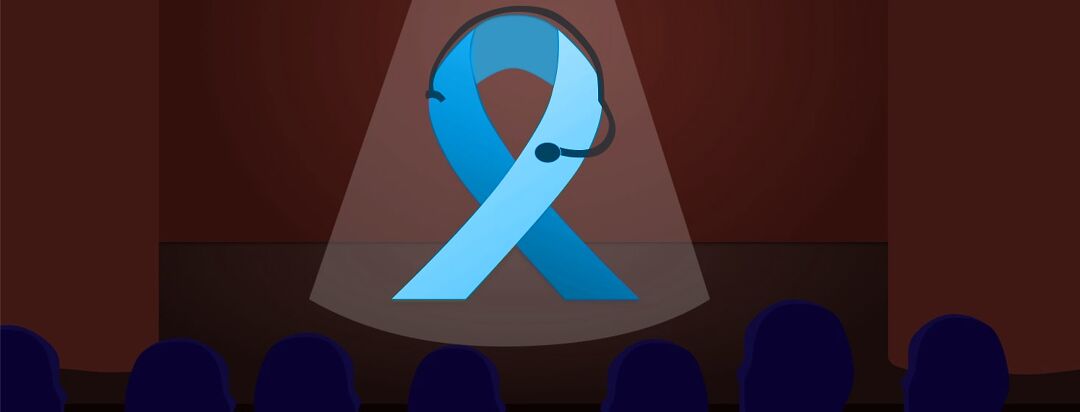 An blue awareness ribbon is wearing a headset standing in the spotlight on a stage presenting to an audience.